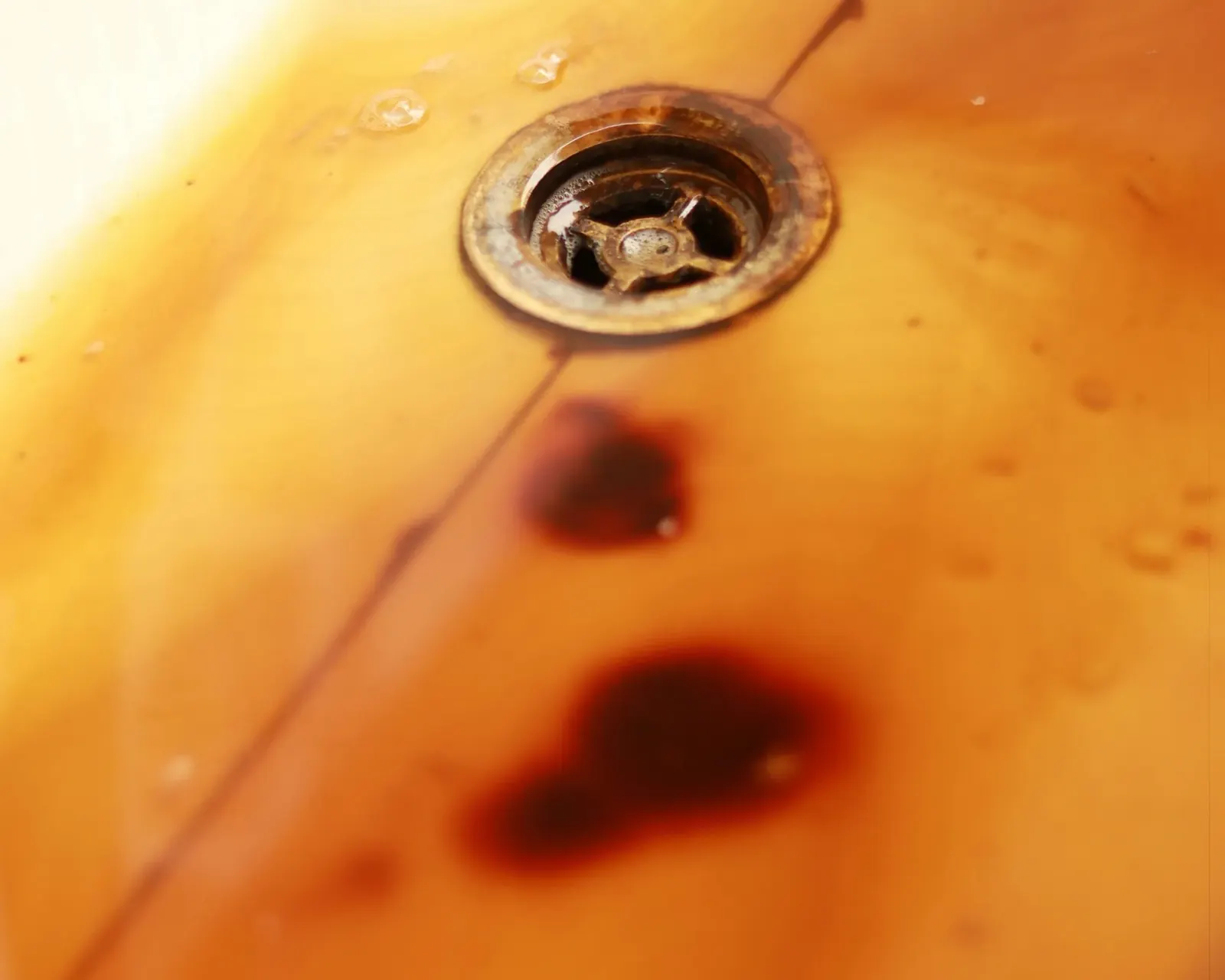 Orange rust stain around a white sink drain