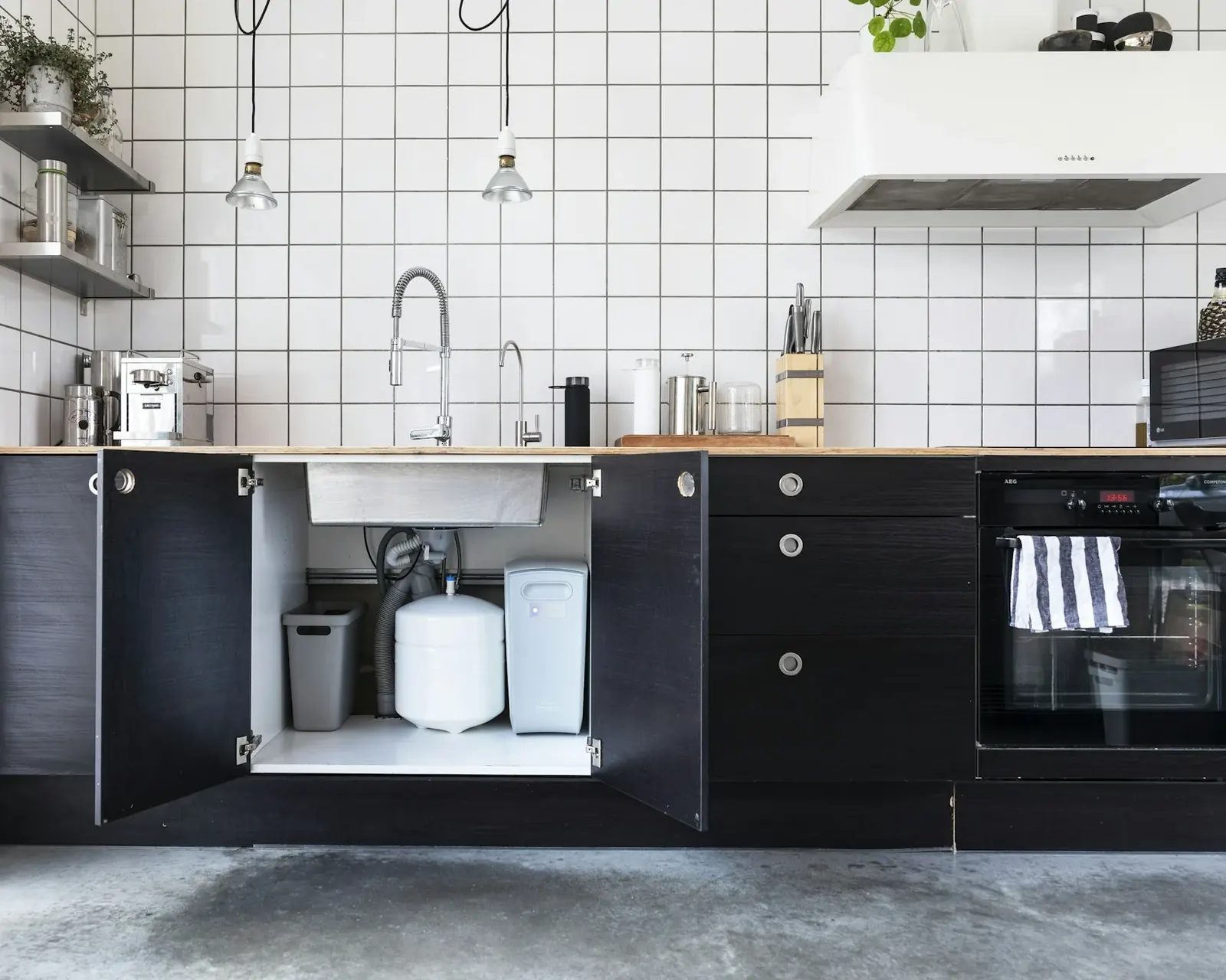 Modern kitchen with an open cabinet showing an under-sink filtration unit