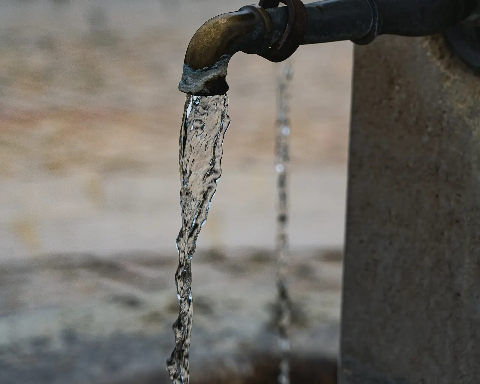 Water flowing from an outdoor tap into a stone basin