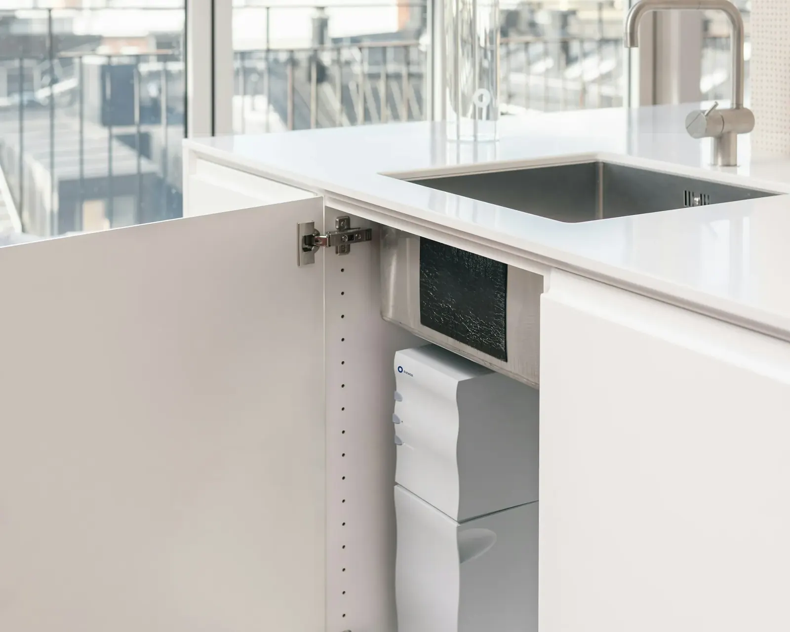 Kitchen sink cabinet open to show a compact filter unit