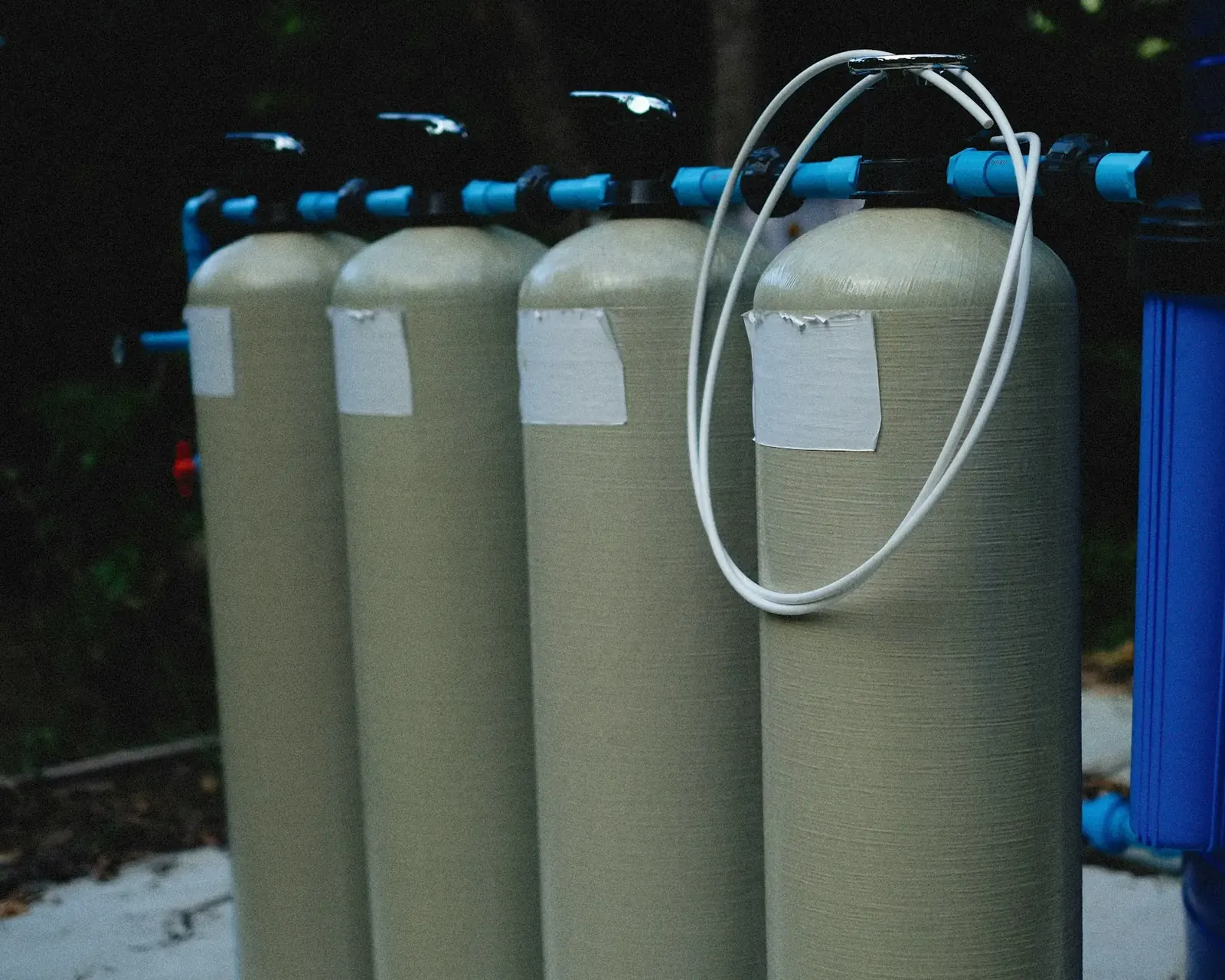 Tall fiberglass water softener tanks connected with blue piping