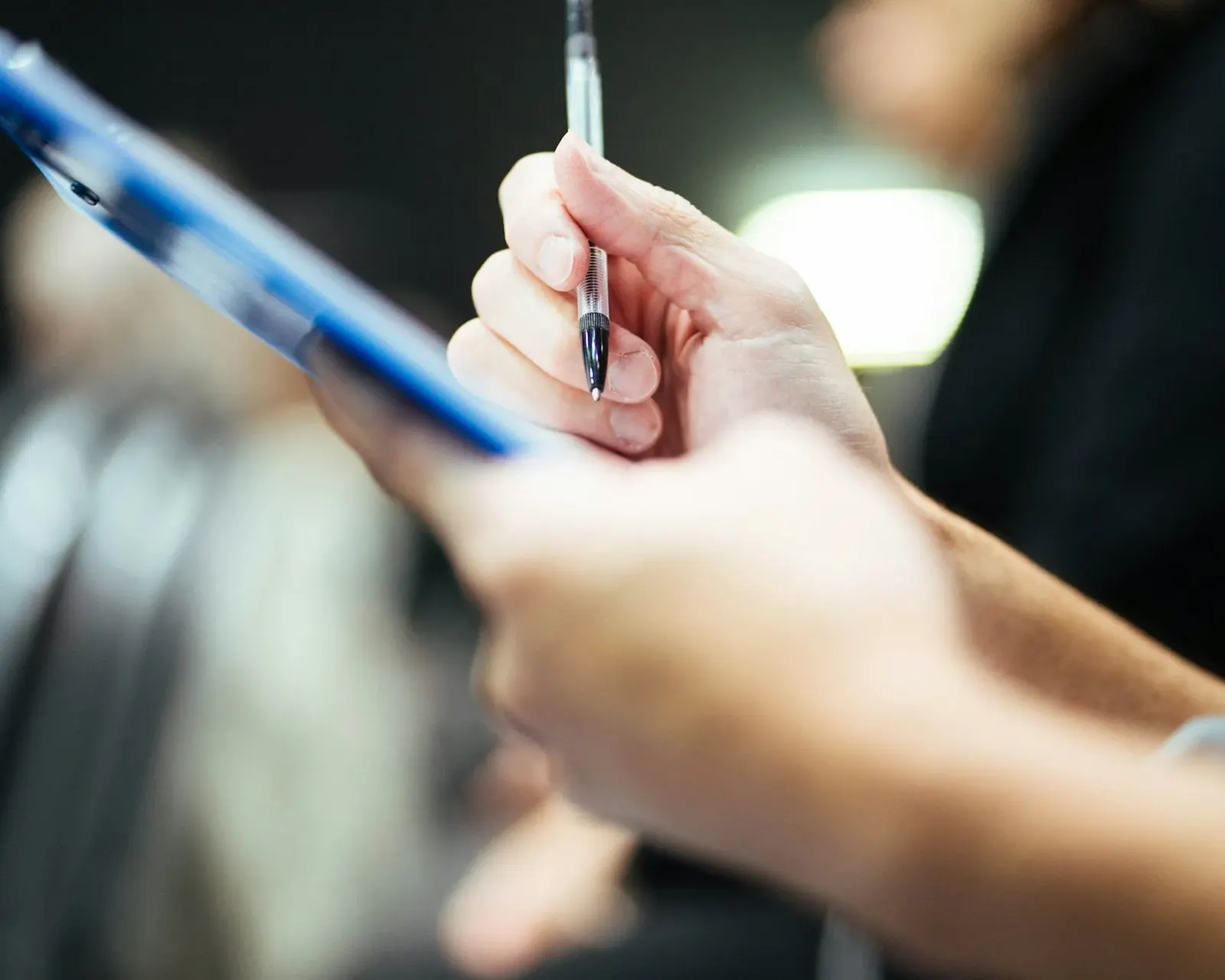 Hand writing notes on a clipboard during a home water assessment