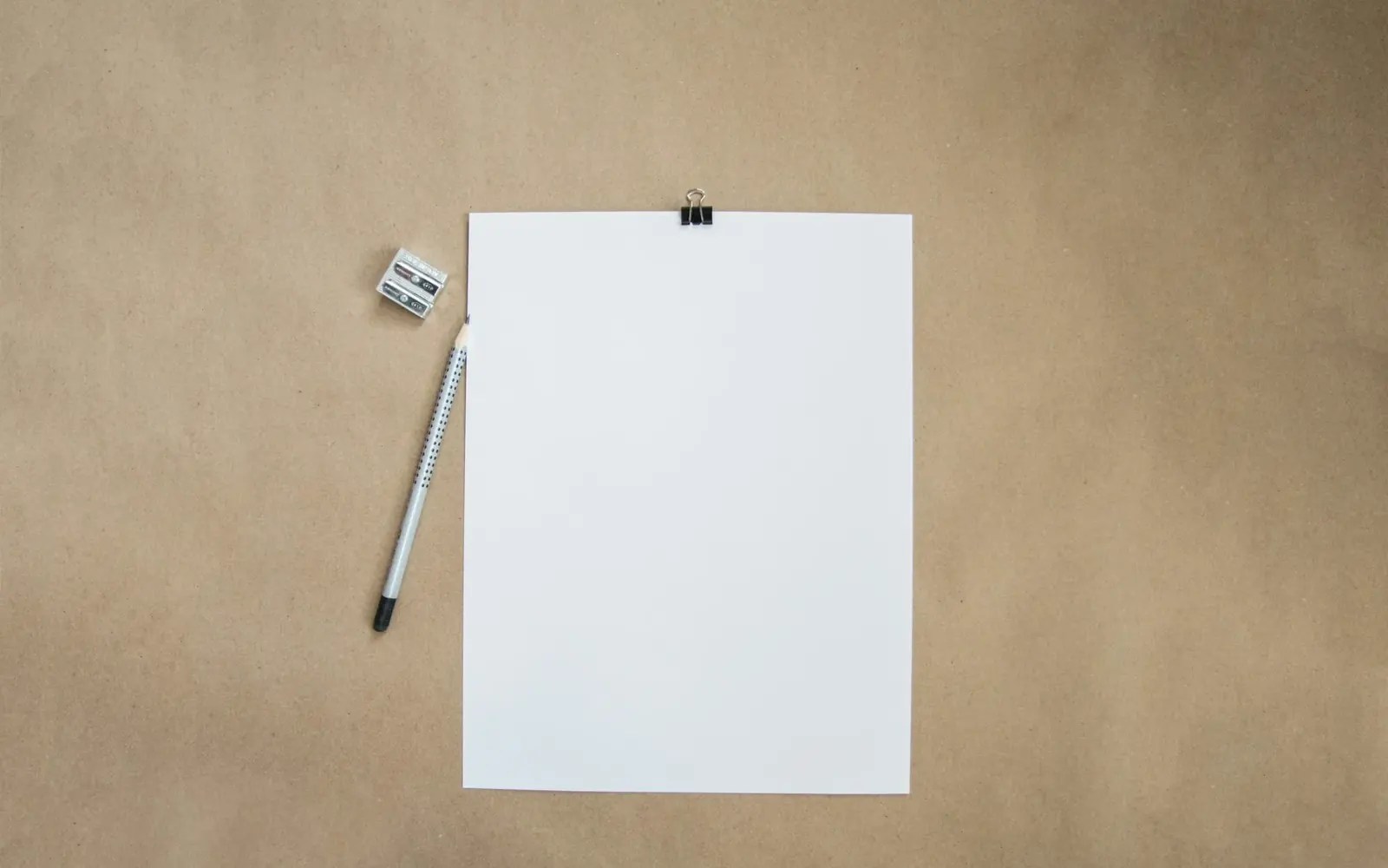 Blank sheet of paper and a pencil on a brown desk