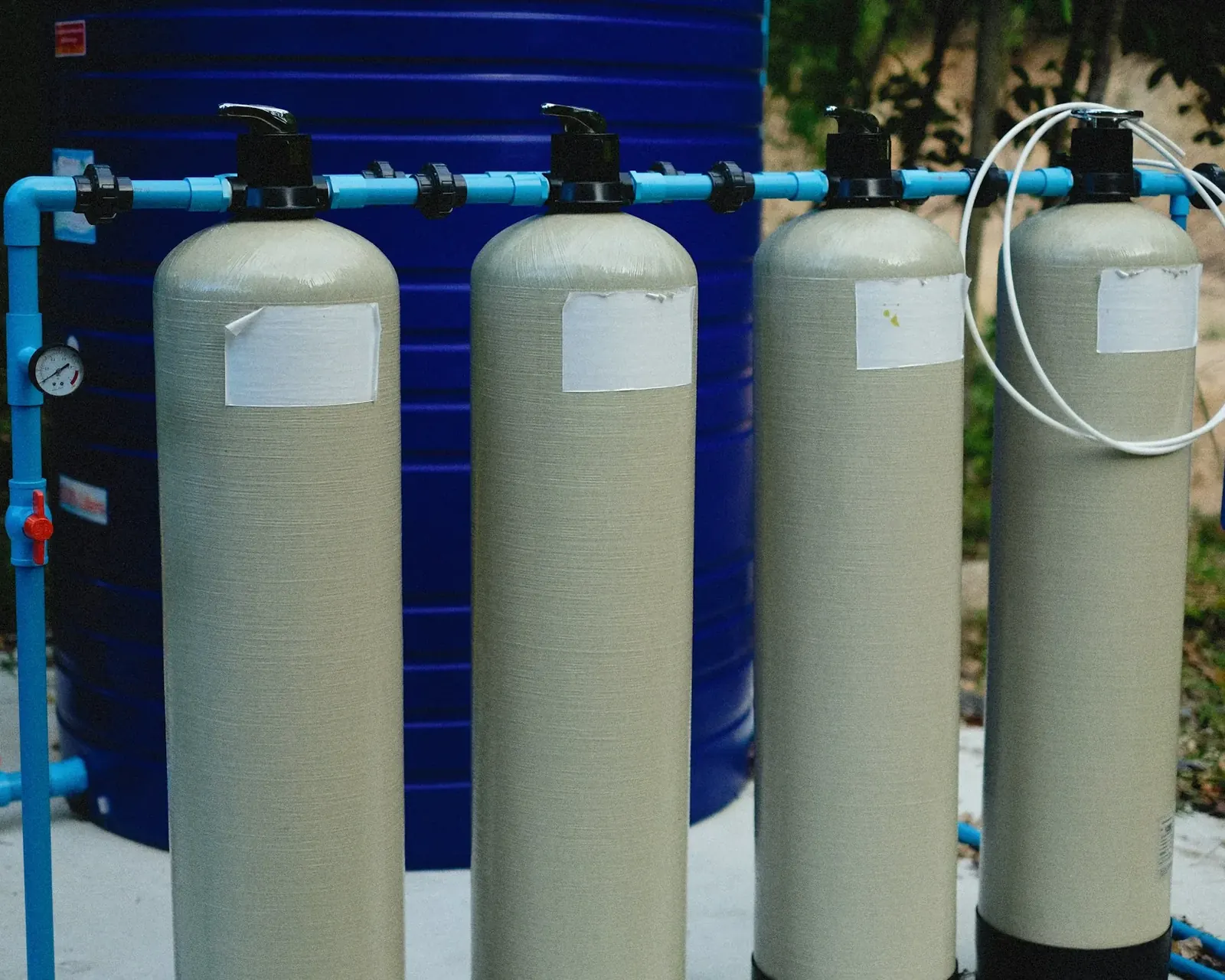 Row of tall water treatment tanks connected with blue piping