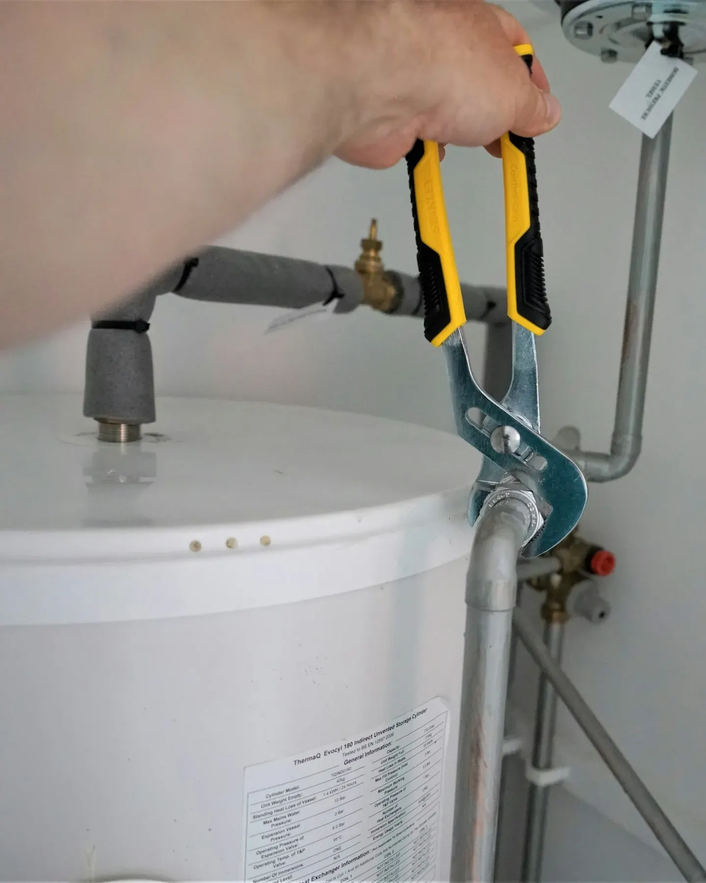 Technician tightening a fitting on a residential water heater with a wrench